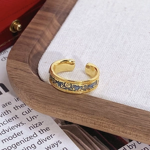 Détail d'une bague dorée vintage avec motifs floraux complexes en émail bleu