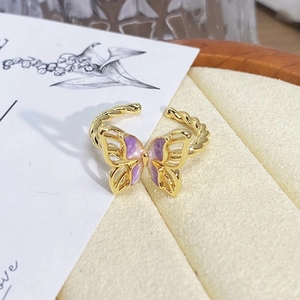 Detailed close-up of purple enamel butterfly ring with gold-plated twisted rope band