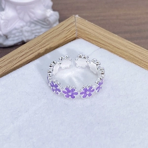 Dettaglio di un anello aperto in argento con fiori di smalto viola e dettagli in zirconia