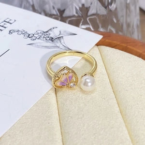 Macro shot of vintage gold open ring with purple enamel butterfly and white pearl detail