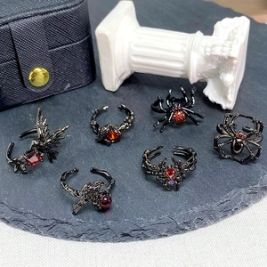Détails de bagues gothiques avec pierres rouges sur métal noir et motifs d'araignée