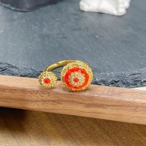 Détail macro d'une bague fleurie orange avec zircons blancs et finition dorée