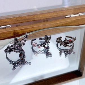 Bagues gothiques en chrome foncé avec zircons rouges et blancs sur un fond en bois