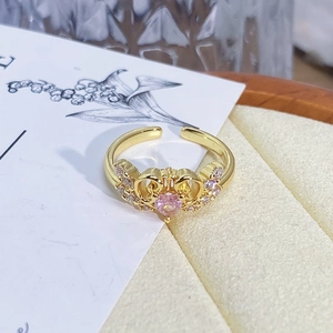 Detailed macro view of an adjustable gold crown ring with a pink heart-shaped stone