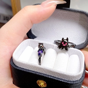 Détail de bagues chat noir et fantôme avec gemme de cœur violette dans un coffret