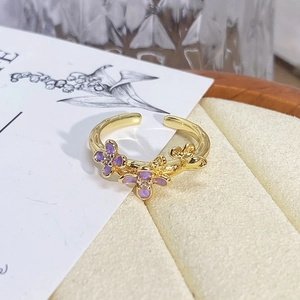 Macro detail of gold vine ring featuring purple enamel flowers and zircon inlay