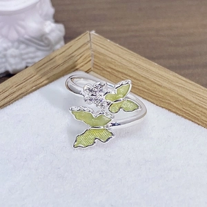 Dettaglio dell'anello d'argento regolabile con farfalle verdi e accenti di fiori