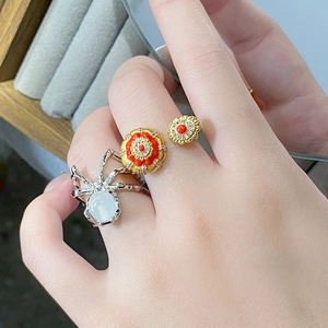 Bague araignée argentée avec opale et bague florale dorée portées sur la main