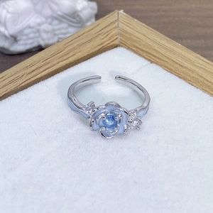 Dettaglio macro di anello regolabile argento con fiore in smalto blu e zircone