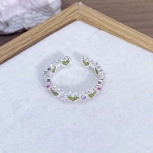 Macro di un anello d'argento regolabile con cuori verde oliva e dettagli in zircone viola