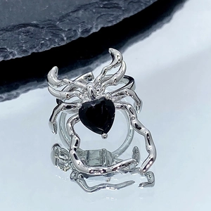 Vue macro d'une bague araignée argentée avec pierre noire en cœur style gothique