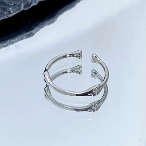 Gros plan d'une bague ajustable en forme d'os argenté avec finition polie