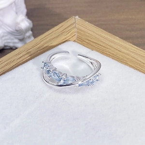 Dettaglio anello regolabile in argento con zirconi azzurri su vassoio in velluto bianco