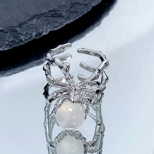 Vue détaillée d'une bague araignée argentée avec opale sur fond réfléchissant