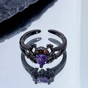Détail macro de la bague grenouille noire punk avec pierre cœur violette et yeux orange