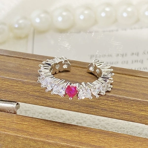 Nahaufnahme eines herzförmigen Zirkonia Rings mit rotem Stein auf Holzständer