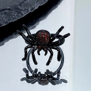 Vue détaillée de la bague araignée gothique noire avec zircons rouges sur fond de pierre