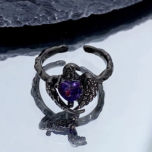 Détail d'une bague gothique noire en forme de cœur avec zircon violet et ailes sombres