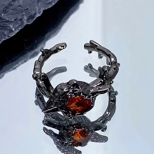 Gros plan détaillé de la bague punk noire avec texture branche et gemme orange