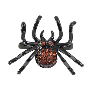 Bague araignée noire gothique sertie de cristaux orange sur un fond blanc neutre