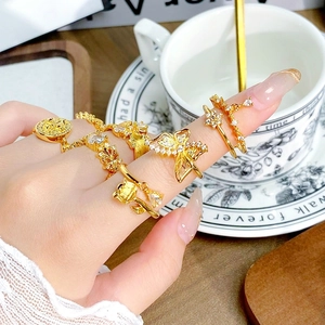 Nahaufnahme von Vintage-Goldringen mit Emaille und Zirkonia an der Hand mit Requisiten