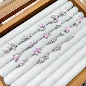 Close-up of sweet pink zircon butterfly and star rings set in a grey jewelry organizer box