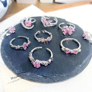 Close-up of adjustable silver rings with pink zircon butterfly and flower charms
