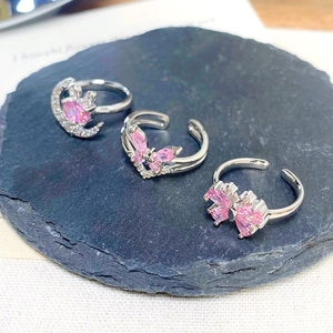 Macro detail of three adjustable silver rings with pink heart and butterfly zircons