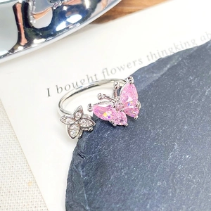 Detailed close-up of silver butterfly ring featuring pink heart-shaped stones and floral accents