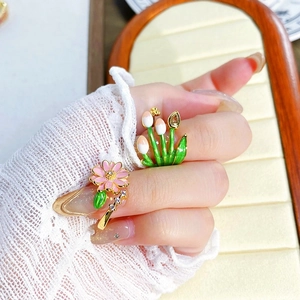 Detail von Vintage Goldringen mit rosa Gänseblümchen und Tulpen Emaille Blumenmuster