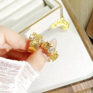Detailansicht goldener Vintage-Ringe mit Emaille und Zirkonia vor Spitzenhintergrund