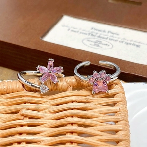 Detail of adjustable silver rings with pink zircon flower and paw print designs