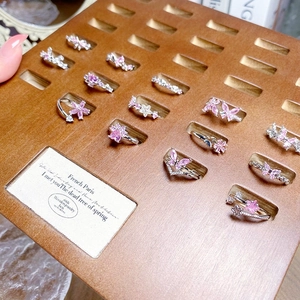 Pink zircon butterfly open rings set in silver finish displayed on wooden tray