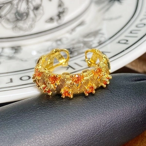 Detail eines goldenen Vintage-Rings mit orangen Zirkonsteinen und strukturierter Oberfläche