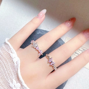 Close-up of pink zircon butterfly and flower rings on model with lace and stone accents