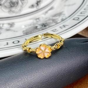 Nahaufnahme des Vintage-Goldrings mit orangefarbenen Emaille-Blüten und Kordelband