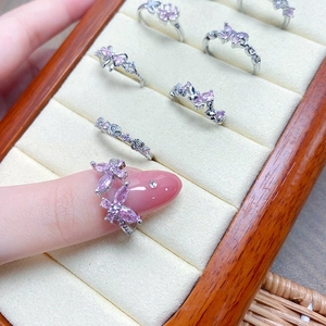 Close-up of pink zircon butterfly and rose rings with silver finish on velvet box