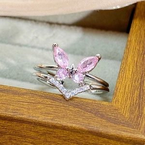 Detailed macro view of silver ring with pink zircon butterfly and V-shaped crystal band