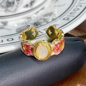 Makroaufnahme: Vintage Goldring mit rosa Emaille-Muster und ovalem Opal-Edelstein-Detail