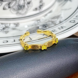 Detaillierte Makroansicht des Vintage-Goldrings mit gelben Emailleblumen und gebürsteter Textur
