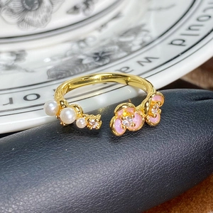 Makro-Detail eines Vintage-Goldrings mit rosa Emaille-Blumen und weißen Perlen besetzt