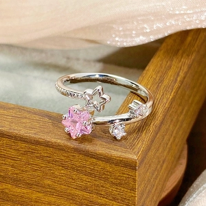 Macro shot of silver adjustable star ring with pink zircon on silk fabric background