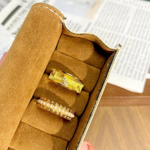 Détail d'une bague vintage dorée avec trèfles et anneau de perles sur velours