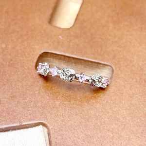 Macro shot of silver ring featuring delicate rose designs and pink zircon gemstones