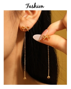 Close-up of golden bow tassel earrings with fine chain dangles on high-grade metal