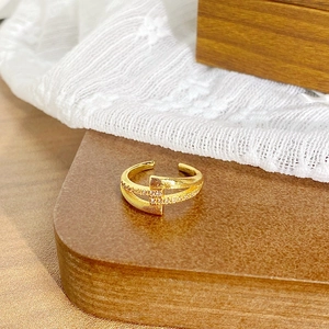 Détail d'une bague dorée réglable avec texture brossée et micro-incrustations de zircons