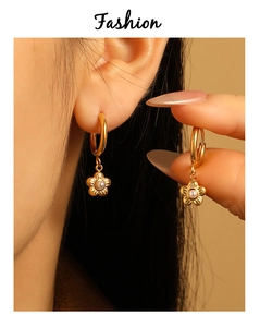 Detail of PVD gold-plated floral earrings with white pearls on a circular hoop
