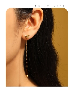 Close-up of heart-shaped gold tassel earrings on model showing elegant dangling chain detail