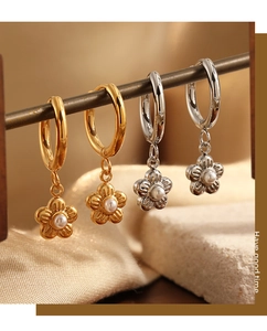 Detailed shot of gold and silver flower hoop earrings with pearls on silk background