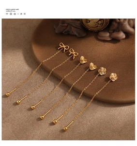 Detailed view of gold tassel earrings featuring bow, heart, and flower shapes in stainless steel